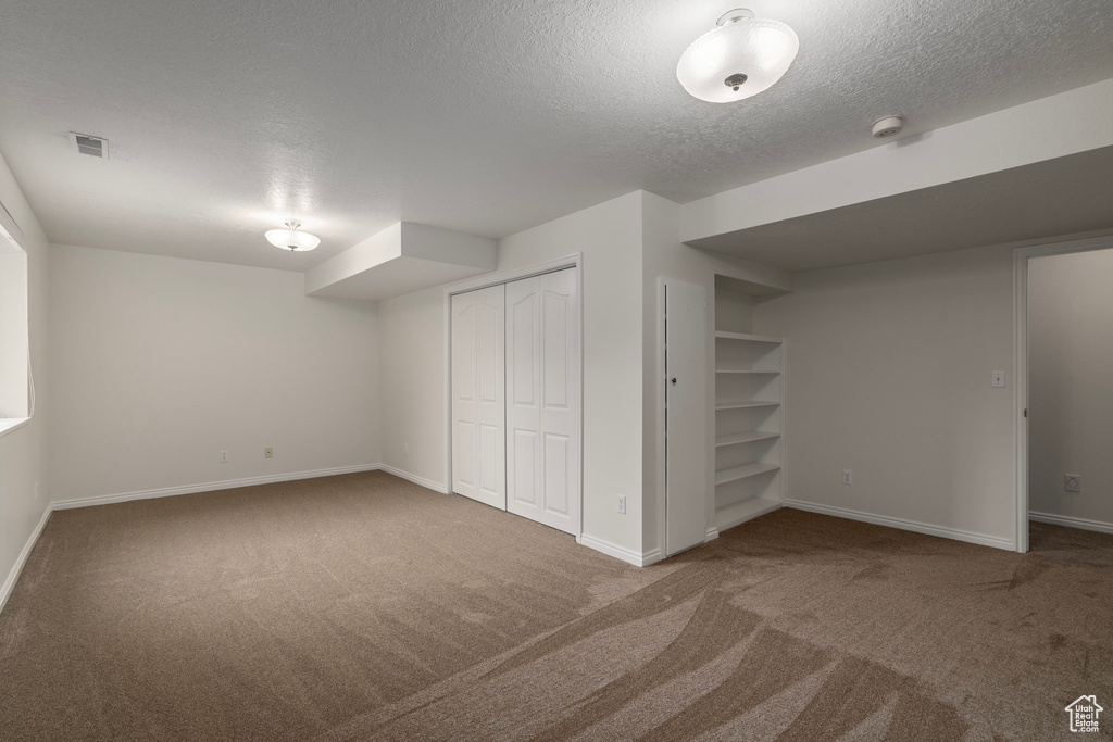 Basement featuring a textured ceiling and carpet flooring