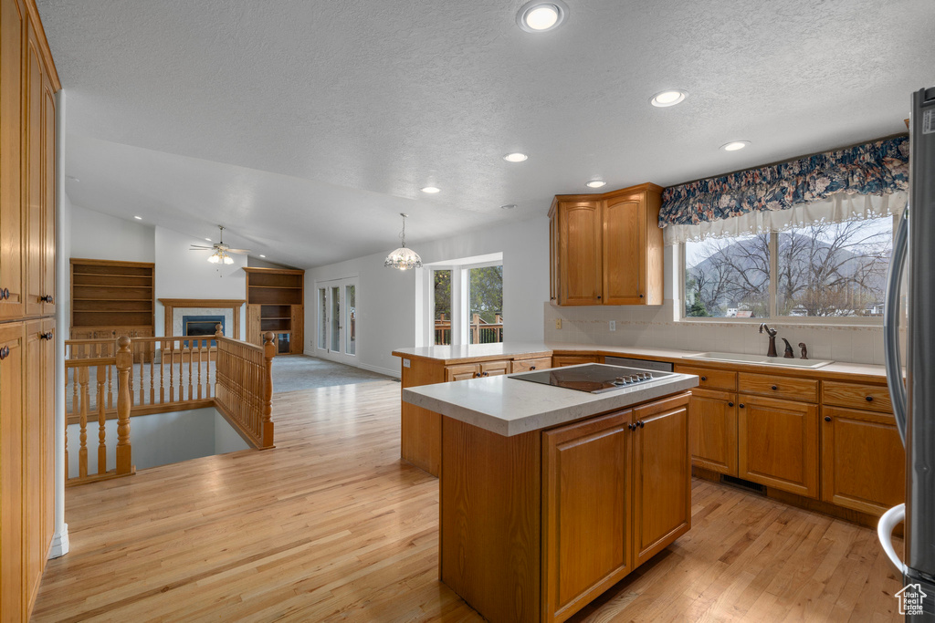 Kitchen with a center island, light hardwood / wood-style floors, sink, and lofted ceiling