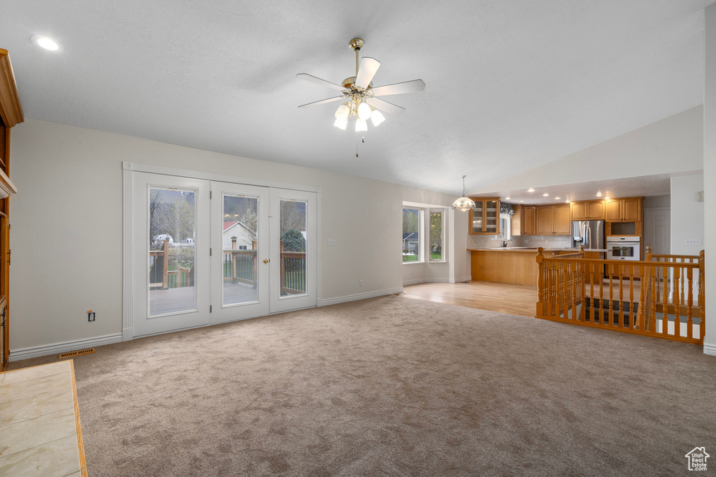 Unfurnished living room with high vaulted ceiling, ceiling fan, and light carpet