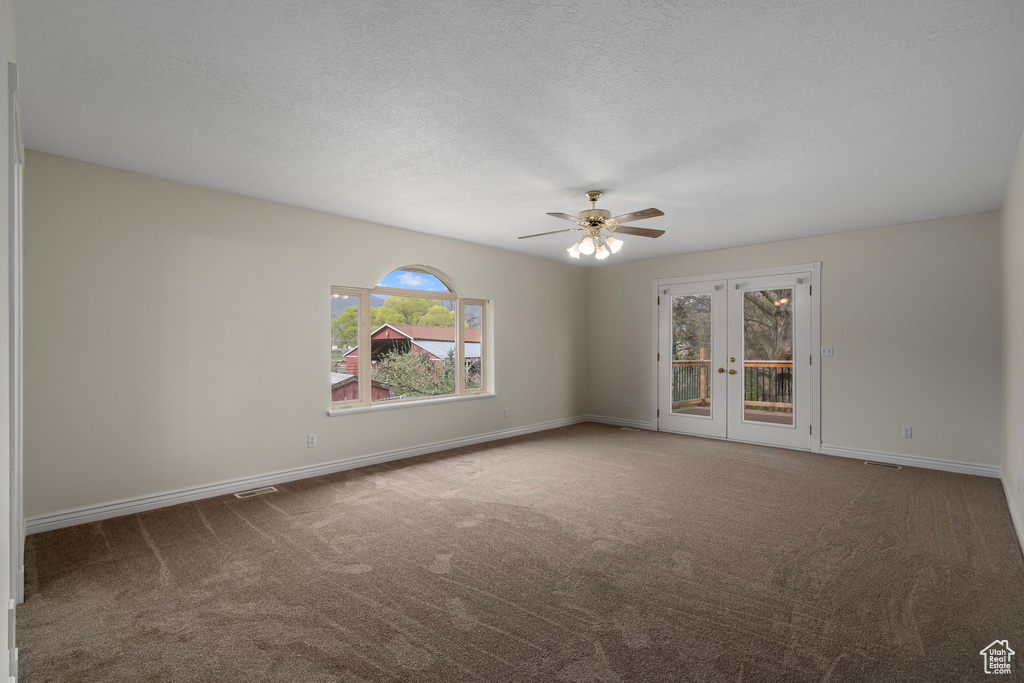 Empty room with french doors, carpet flooring, ceiling fan, and a textured ceiling