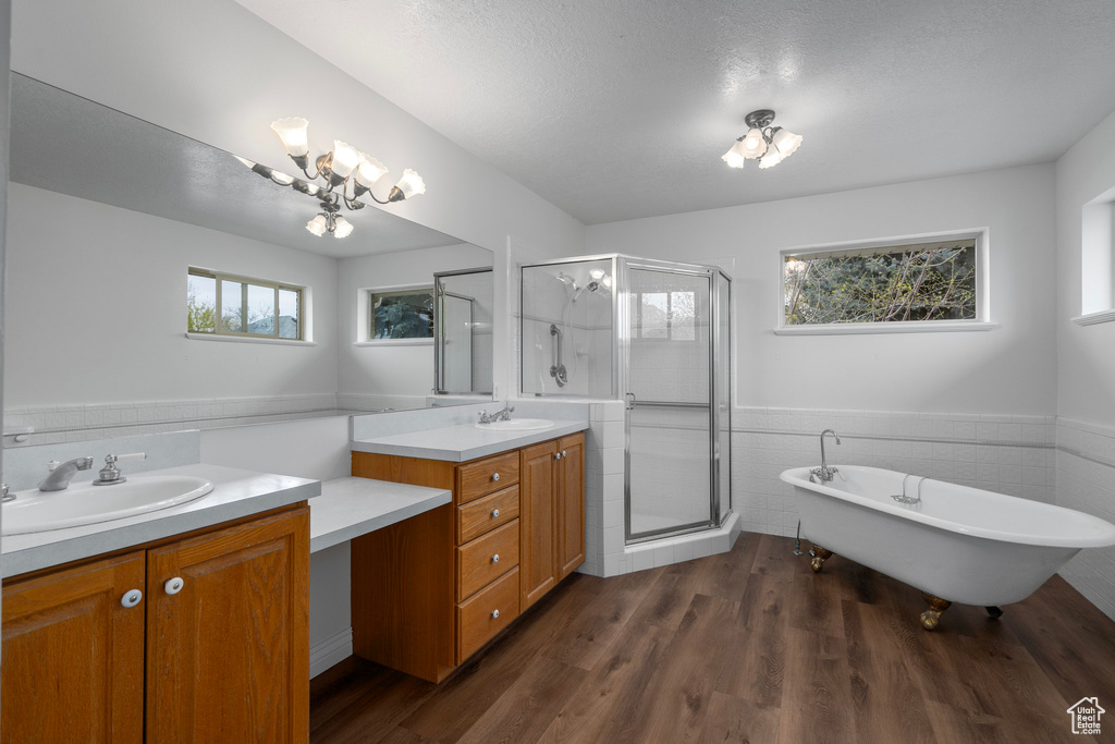 Bathroom with a textured ceiling, vanity, hardwood / wood-style floors, and plus walk in shower