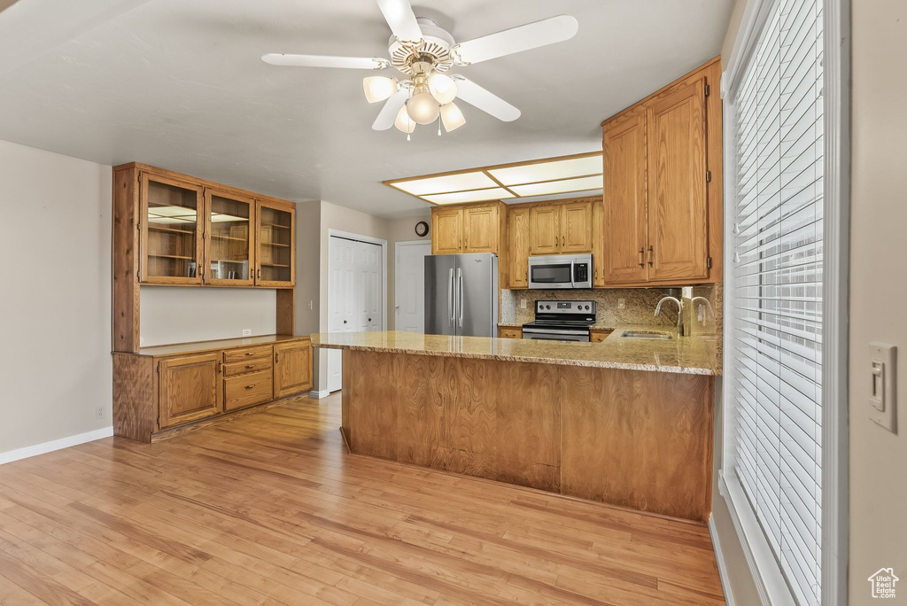 Kitchen featuring light stone counters, light hardwood / wood-style flooring, kitchen peninsula, and stainless steel appliances