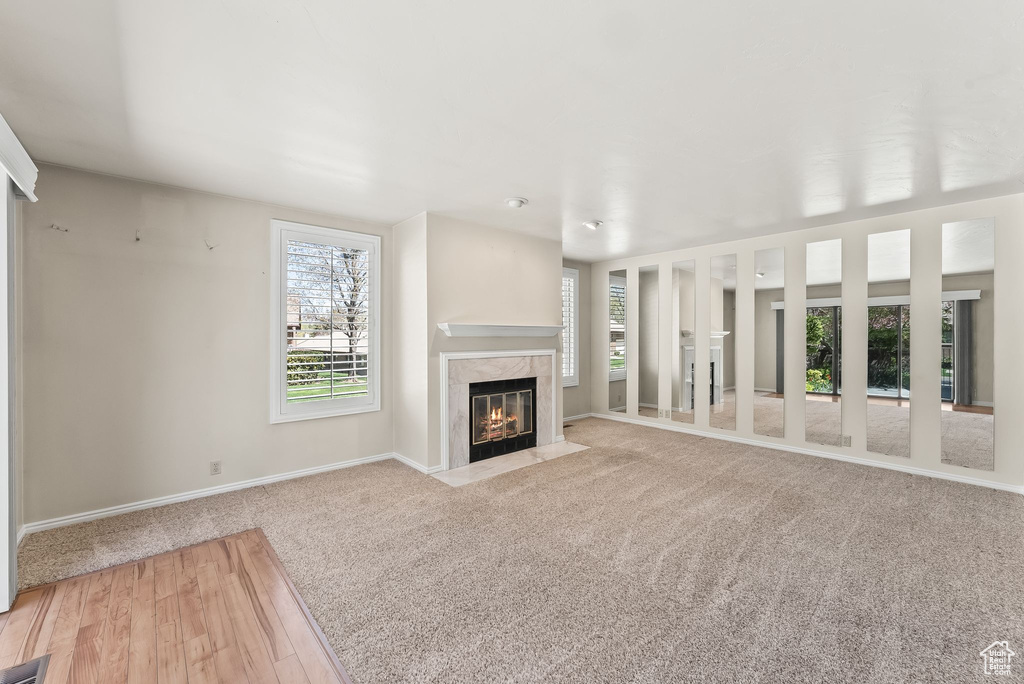 Unfurnished living room featuring a high end fireplace and light colored carpet