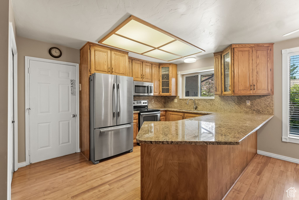 Kitchen featuring light hardwood / wood-style flooring, stainless steel appliances, and kitchen peninsula
