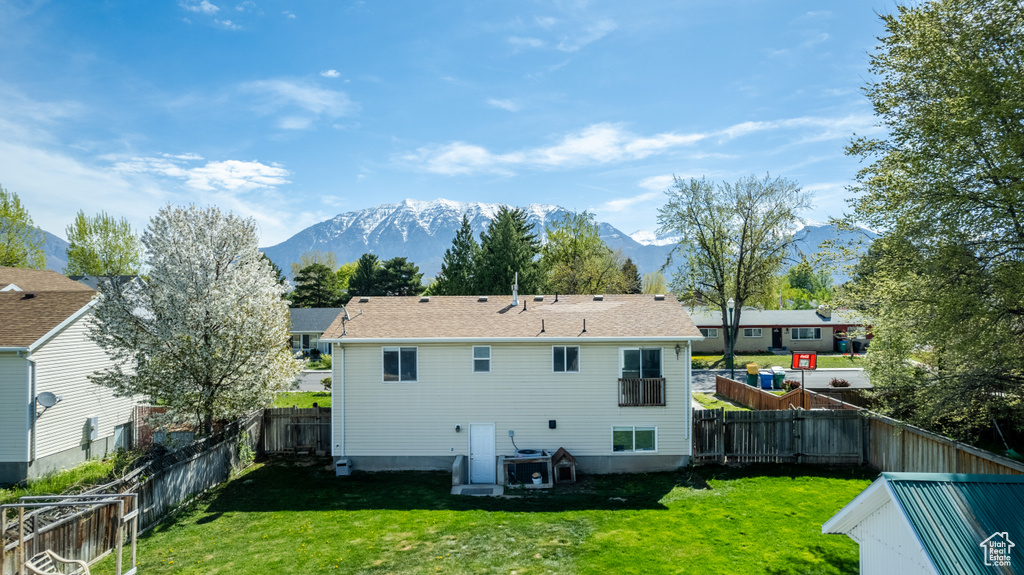 Rear view of property with a mountain view and a lawn