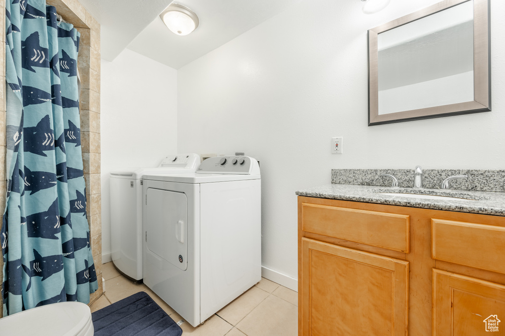 Laundry area with sink, separate washer and dryer, and light tile floors