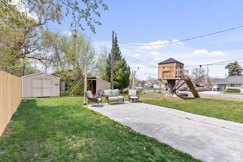 View of yard with a playground, an outdoor living space, a patio, and a storage shed