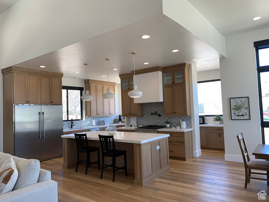 Kitchen with hanging light fixtures, a center island, hardwood / wood-style flooring, and high end refrigerator