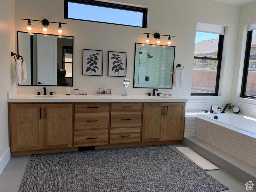 Bathroom with double vanity, tile floors, and tiled bath