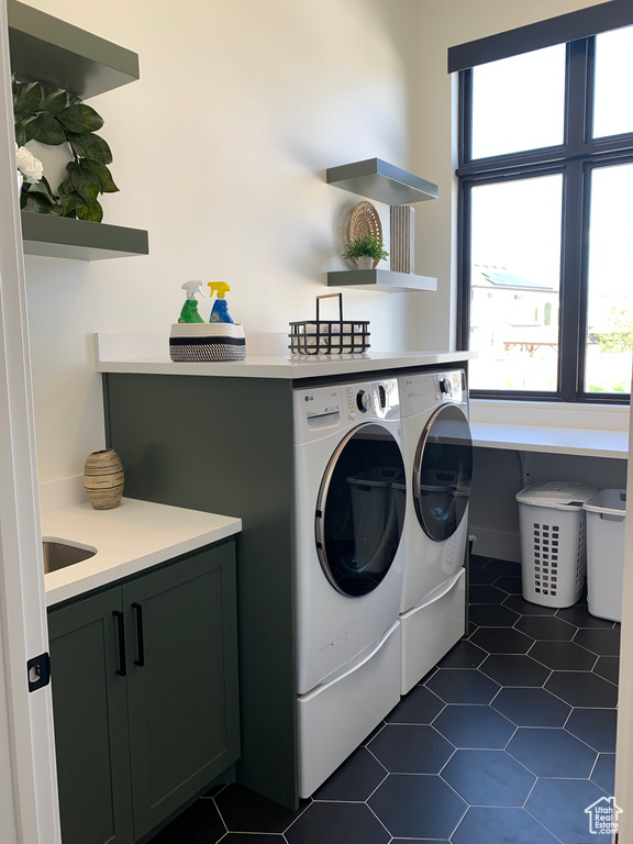 Washroom featuring cabinets, dark tile flooring, and separate washer and dryer