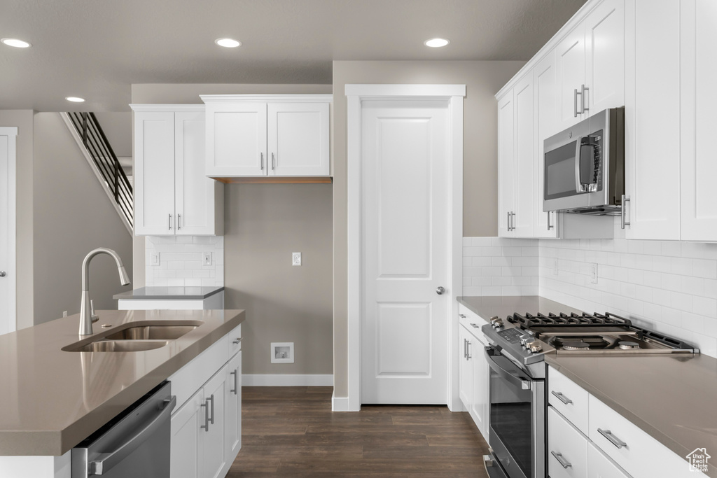 Kitchen with backsplash, stainless steel appliances, dark hardwood / wood-style floors, white cabinets, and sink