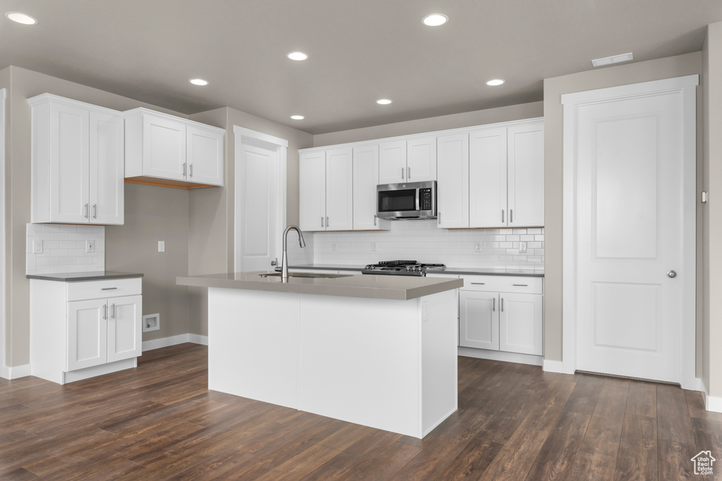 Kitchen featuring white cabinets, tasteful backsplash, and dark wood-type flooring