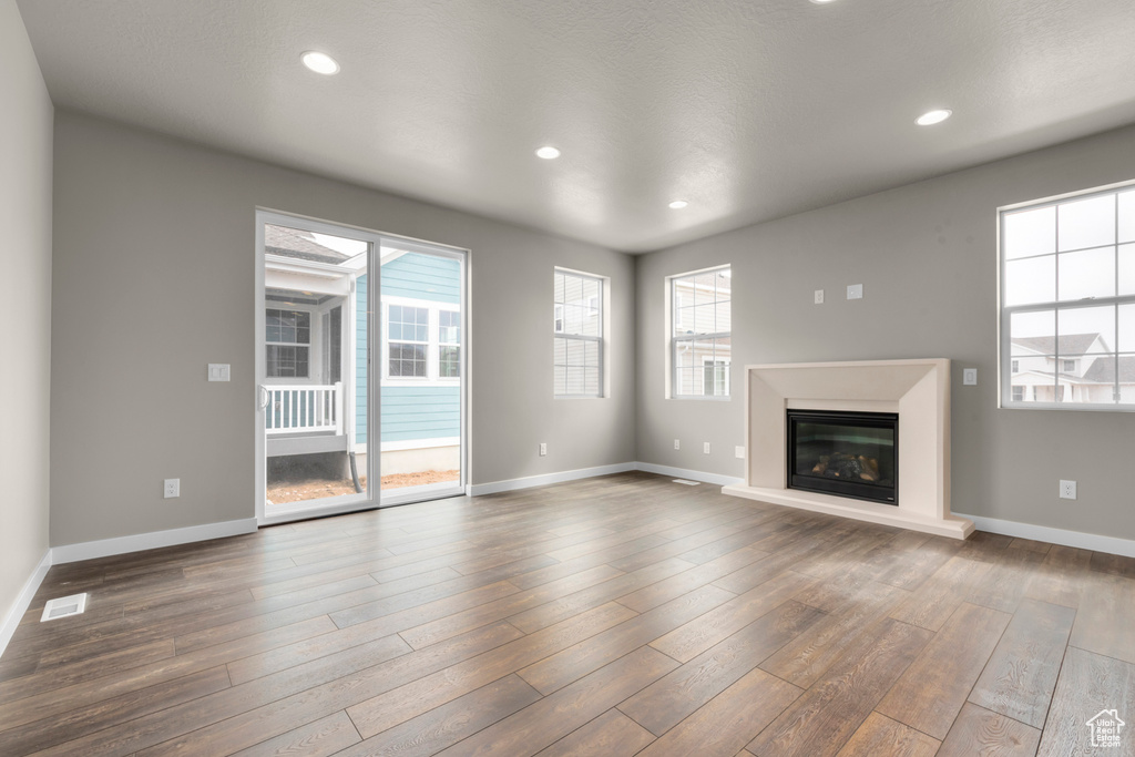 Unfurnished living room featuring dark hardwood / wood-style flooring and a healthy amount of sunlight