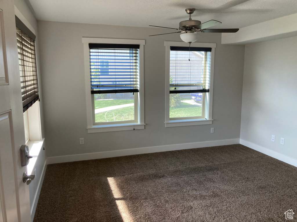 Unfurnished room featuring carpet flooring, a healthy amount of sunlight, and ceiling fan