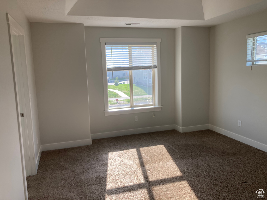 Unfurnished room with a wealth of natural light and dark colored carpet