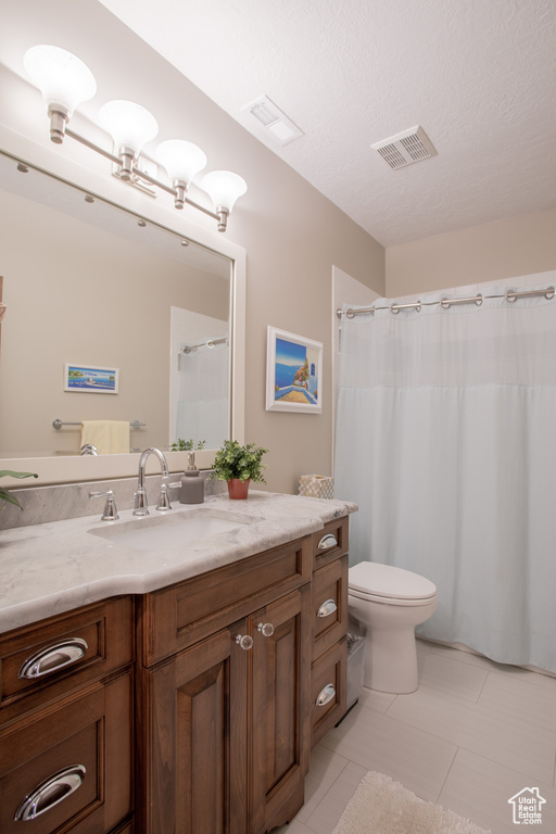 Bathroom featuring toilet, oversized vanity, a textured ceiling, and tile flooring
