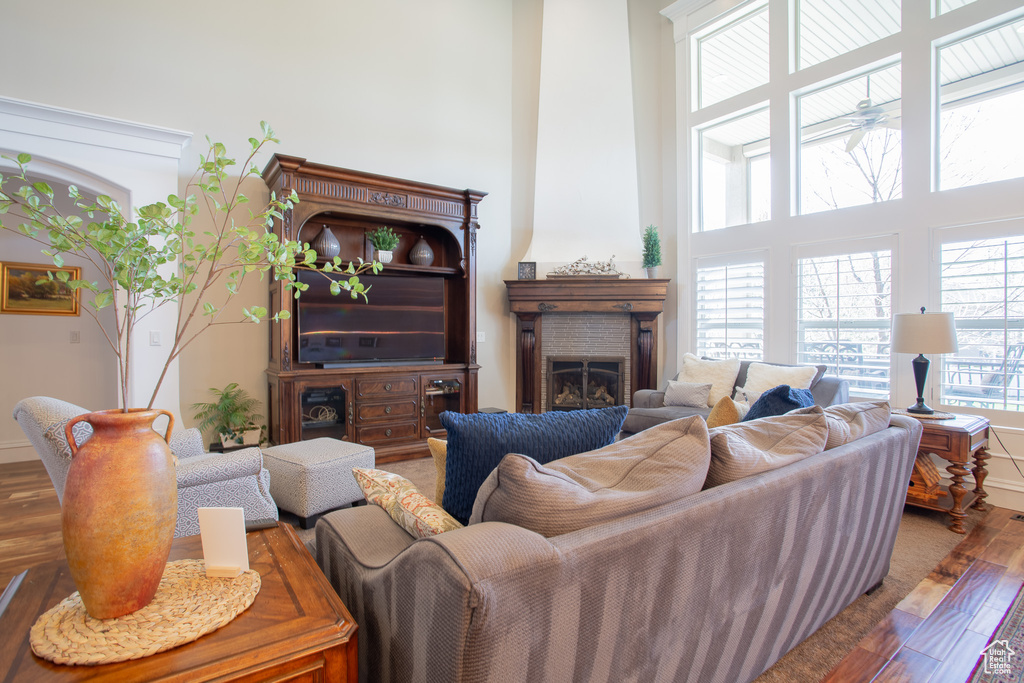 Living room with a towering ceiling, hardwood / wood-style flooring, and a brick fireplace