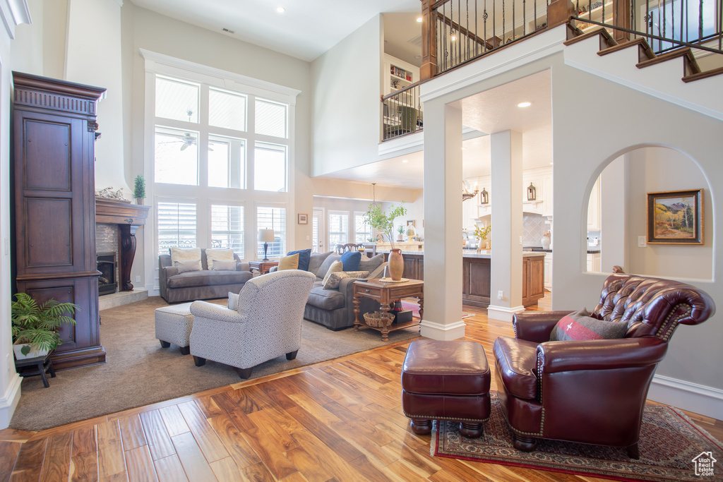 Living room featuring ceiling fan, hardwood / wood-style floors, and a towering ceiling