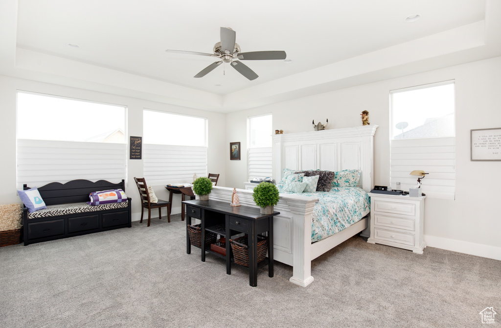 Bedroom featuring light colored carpet, ceiling fan, and a raised ceiling