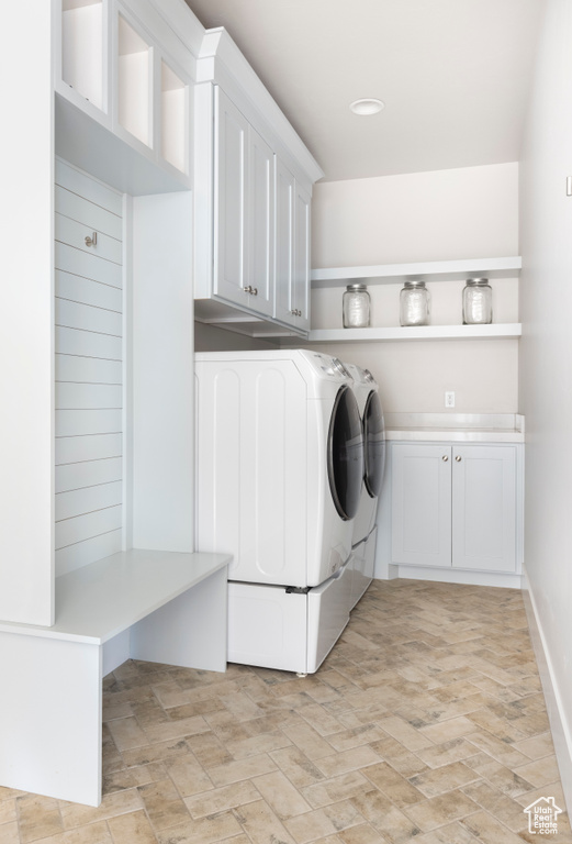 Laundry area featuring washing machine and dryer, cabinets, and light tile floors