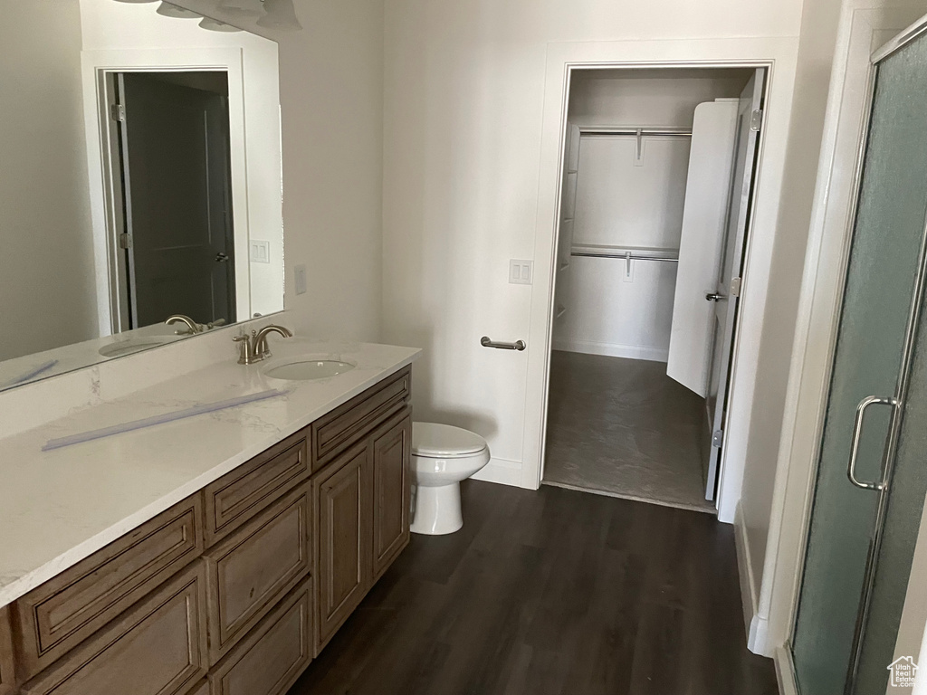 Bathroom with hardwood / wood-style flooring, toilet, vanity, and walk in shower