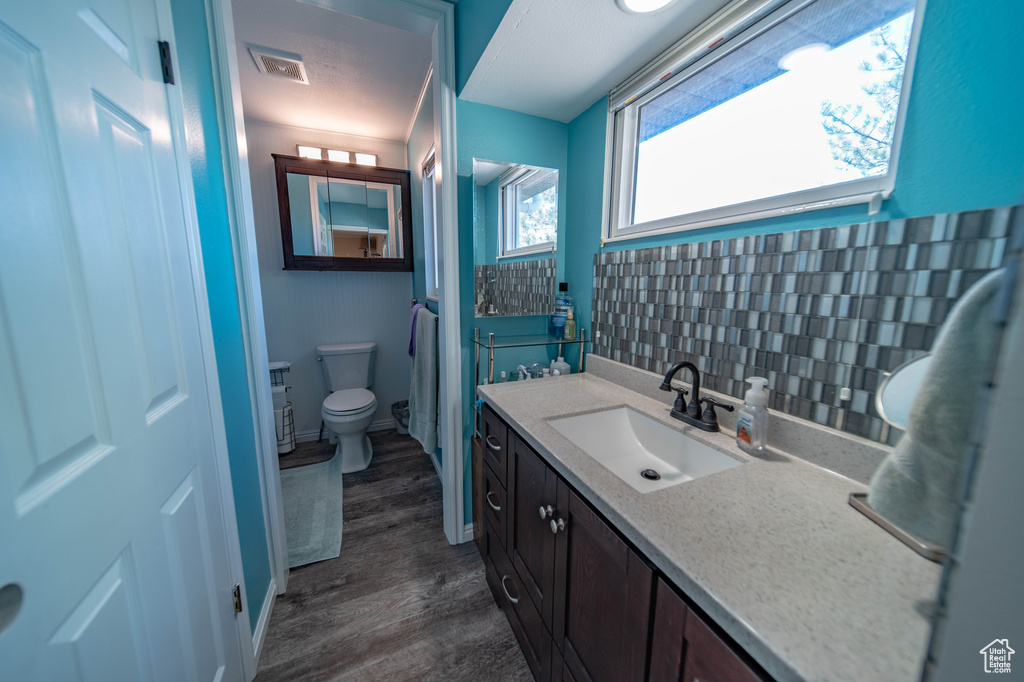 Bathroom featuring backsplash, vanity, toilet, and hardwood / wood-style flooring