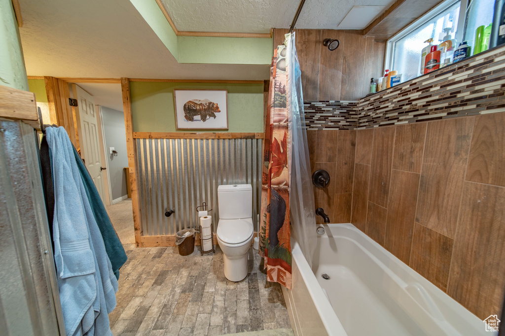 Bathroom featuring hardwood / wood-style flooring, toilet, and shower / tub combo with curtain