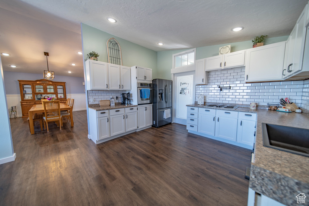 Kitchen featuring appliances with stainless steel finishes, tasteful backsplash, dark hardwood / wood-style flooring, and white cabinets