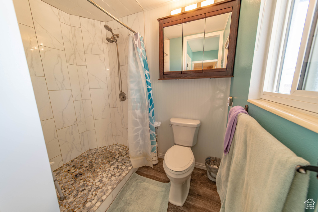 Bathroom with curtained shower, hardwood / wood-style floors, and toilet