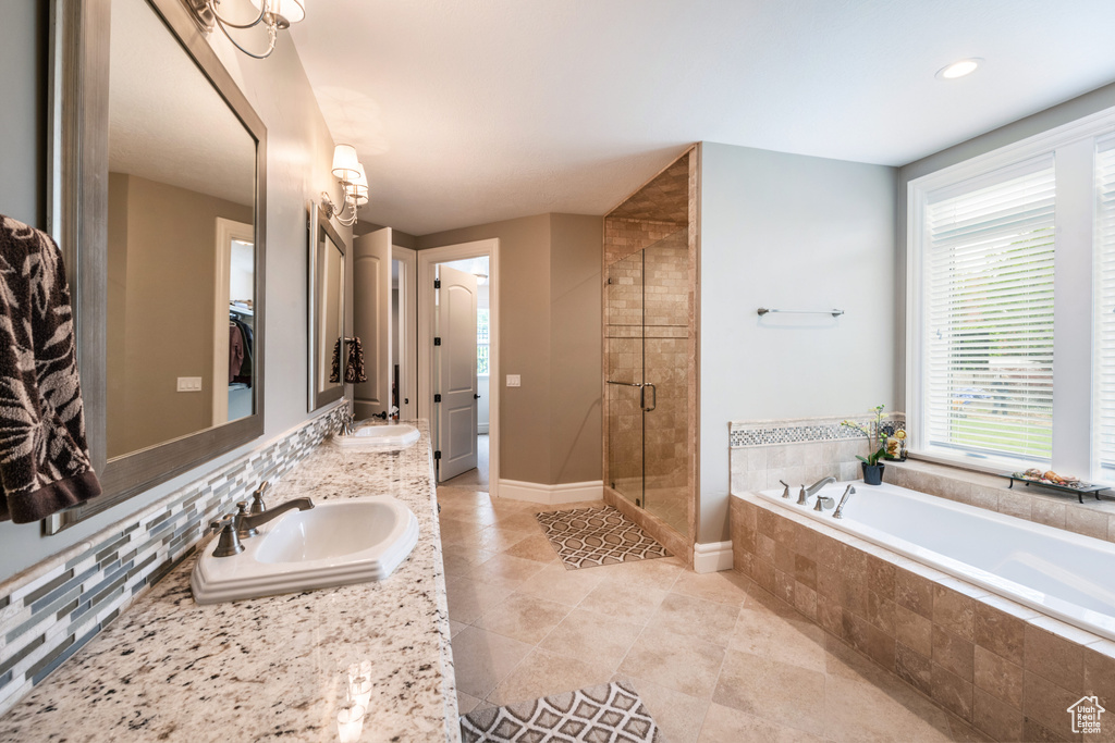 Bathroom featuring oversized vanity, tasteful backsplash, shower with separate bathtub, double sink, and tile floors
