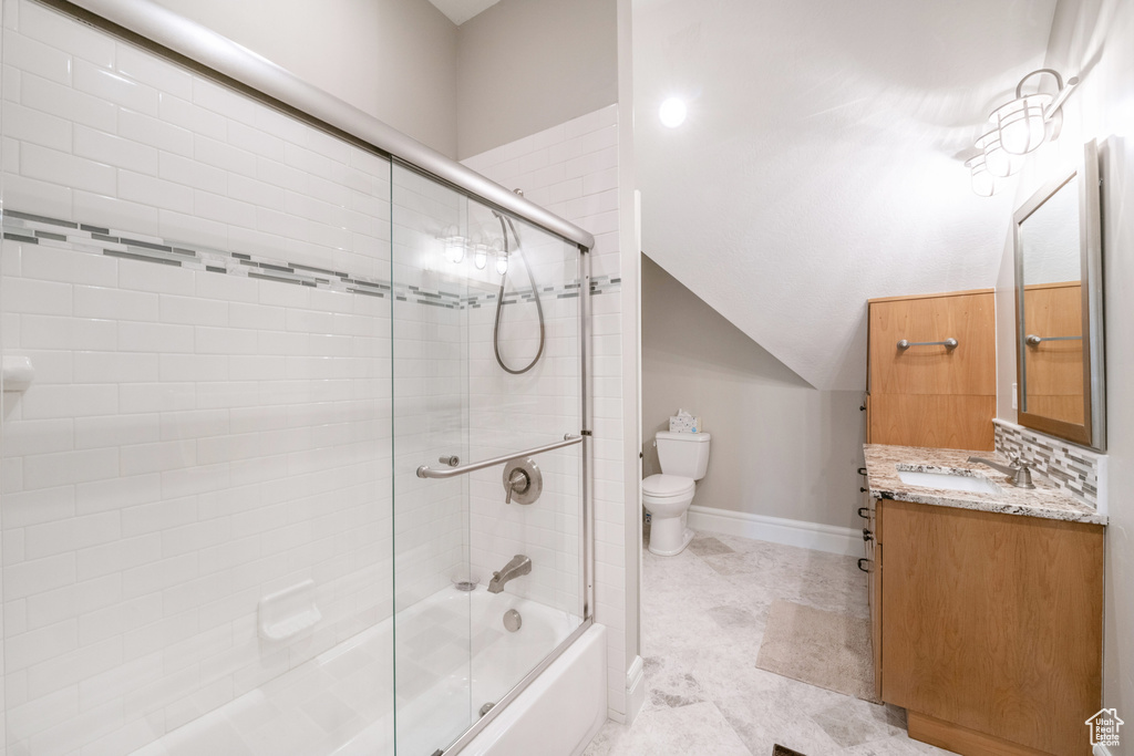 Full bathroom with tile floors, vanity, backsplash, enclosed tub / shower combo, and toilet