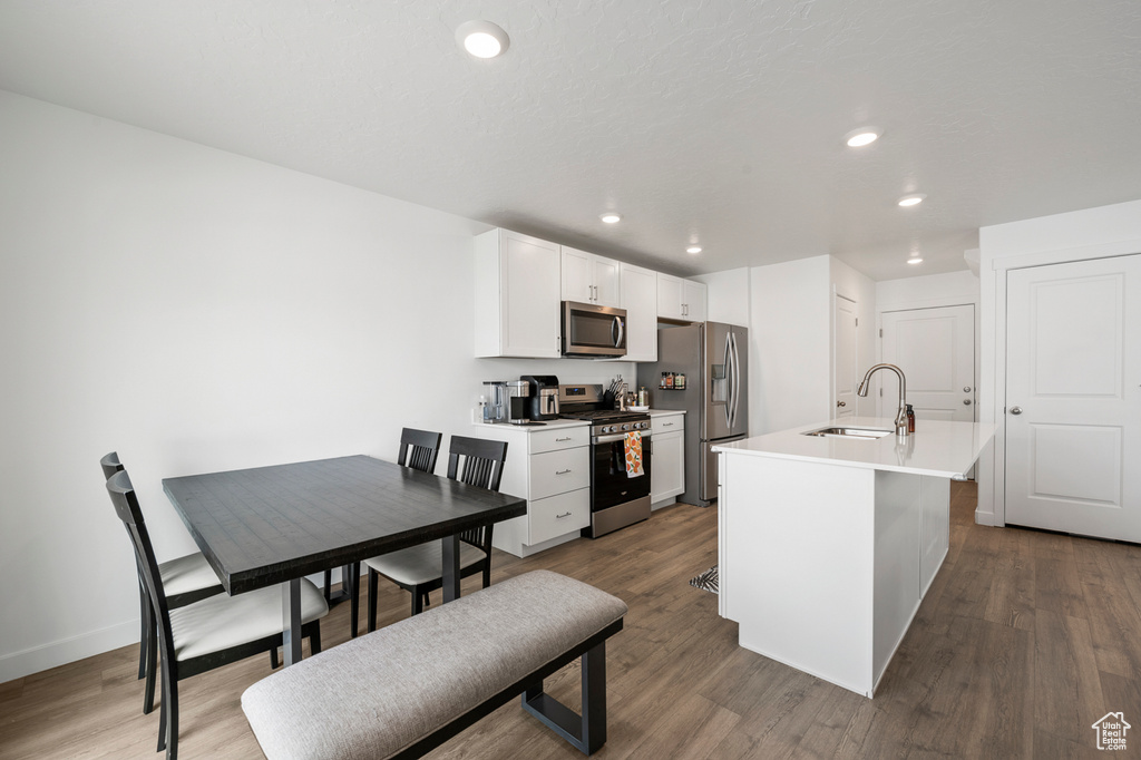 Kitchen featuring hardwood / wood-style floors, sink, appliances with stainless steel finishes, and white cabinetry