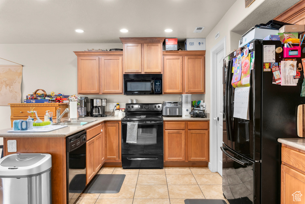 Kitchen featuring sink, kitchen peninsula, light tile flooring, and black appliances