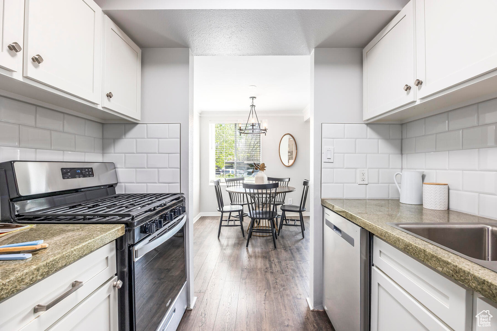 Kitchen featuring backsplash, white cabinetry, dark hardwood / wood-style flooring, crown molding, and stainless steel appliances