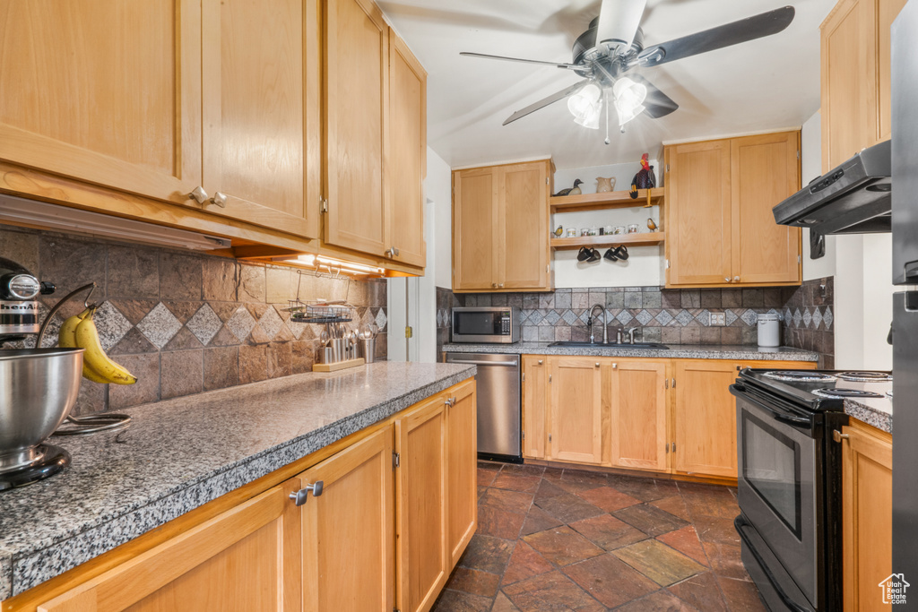 Kitchen with ceiling fan, sink, dark tile flooring, backsplash, and stainless steel appliances