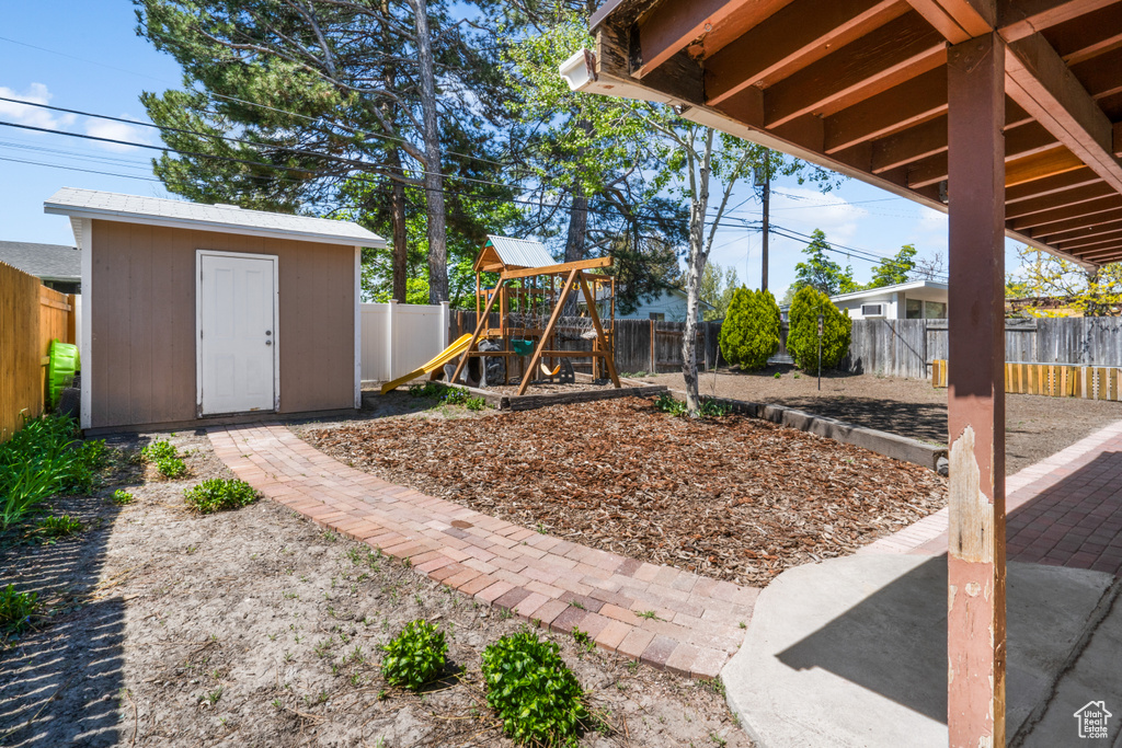 View of yard featuring a playground and a storage shed