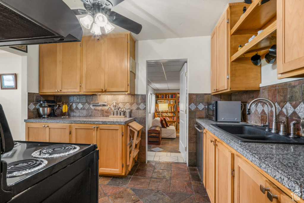 Kitchen with light brown cabinets, custom range hood, tasteful backsplash, dark tile flooring, and ceiling fan