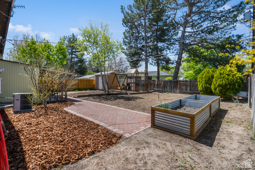 View of yard featuring central AC, an outdoor structure, a playground, and a patio