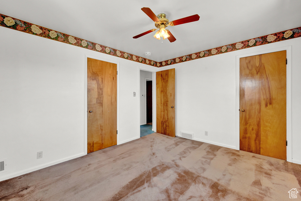 Unfurnished bedroom with multiple closets, ceiling fan, and carpet flooring