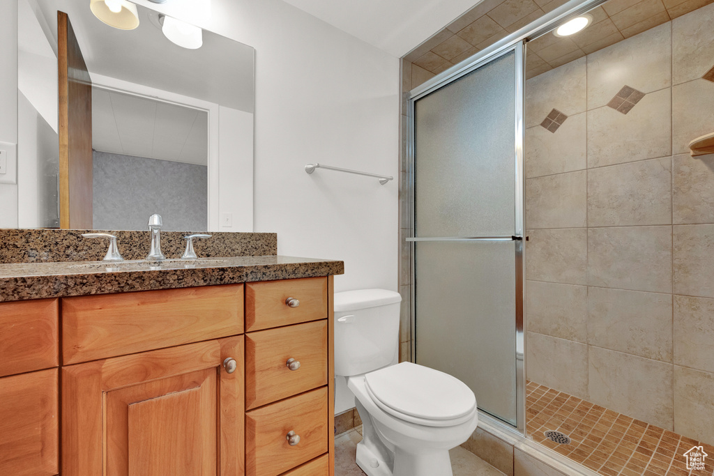 Bathroom with an enclosed shower, toilet, tile flooring, and large vanity