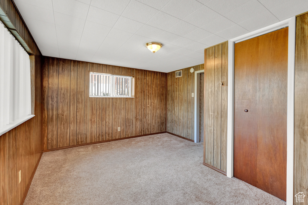 Unfurnished bedroom featuring light colored carpet and wooden walls