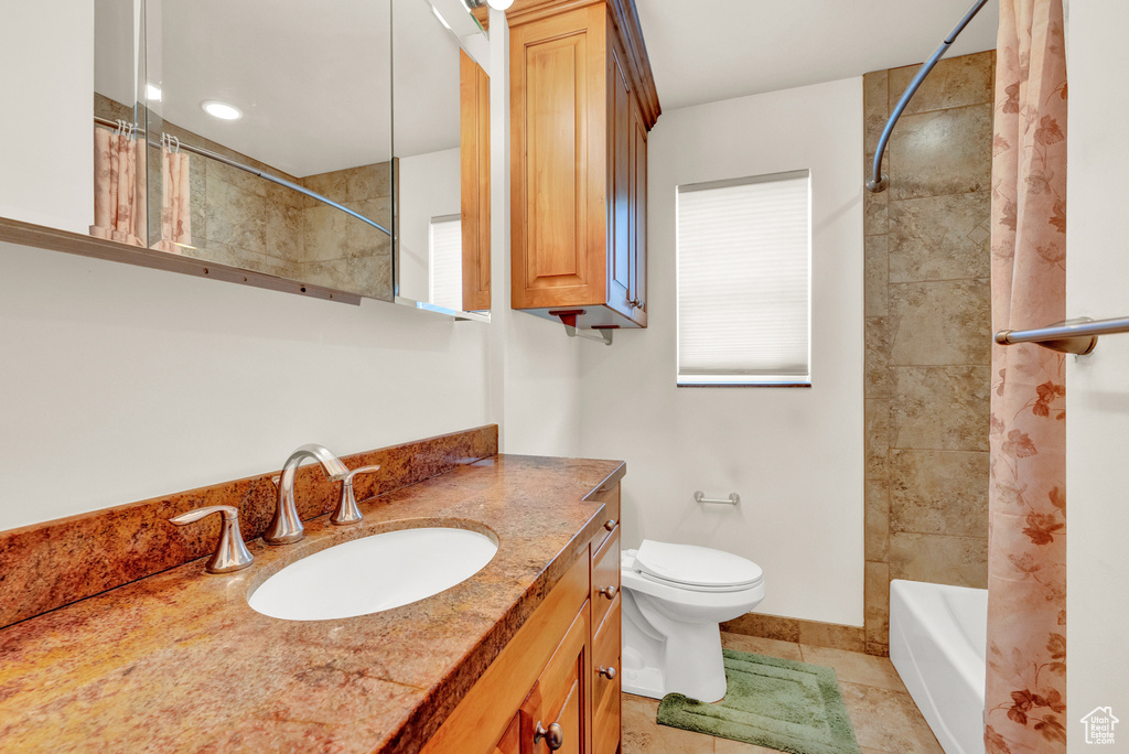 Full bathroom featuring oversized vanity, toilet, tile floors, and shower / bathtub combination with curtain