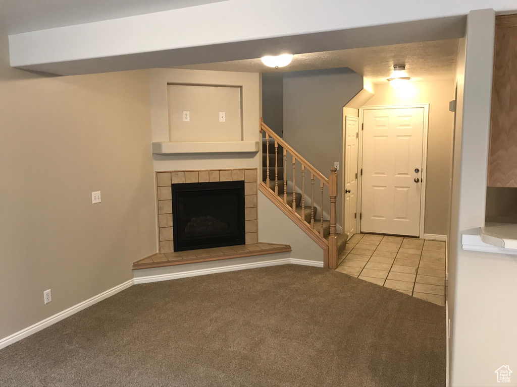 Unfurnished living room featuring carpet flooring and a tile fireplace
