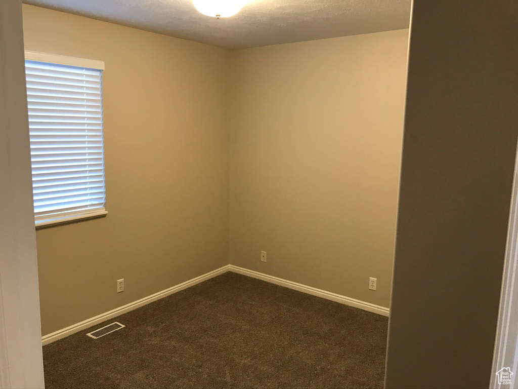 Spare room with a healthy amount of sunlight and dark colored carpet