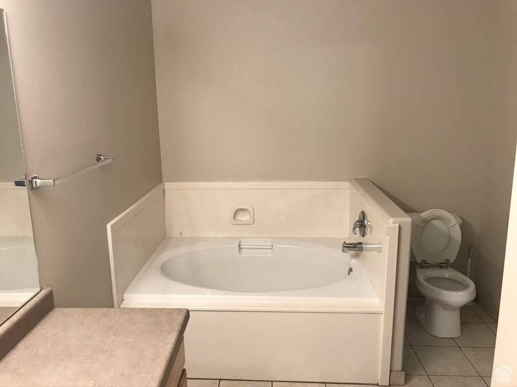 Bathroom featuring a tub, tile floors, and toilet