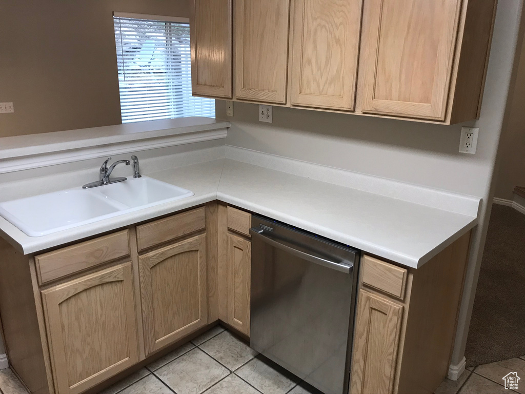 Kitchen with stainless steel dishwasher, sink, and light tile floors
