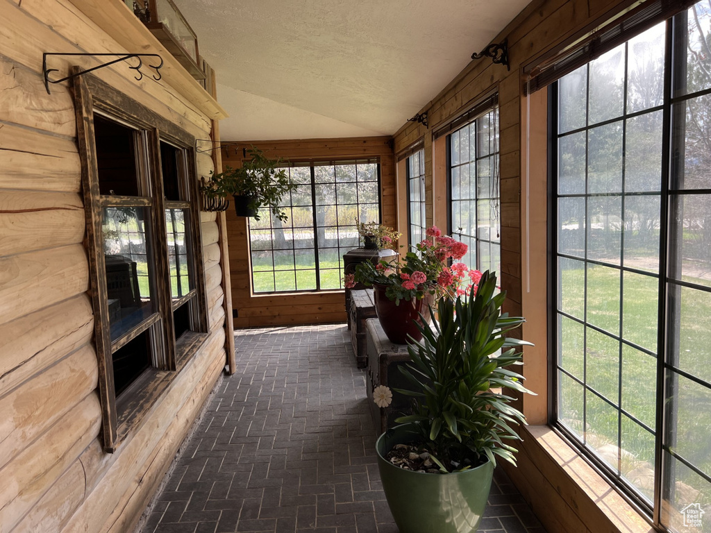 Unfurnished sunroom featuring lofted ceiling