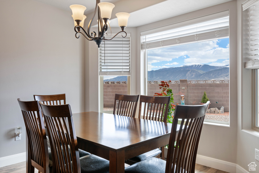 Dining area with a healthy amount of sunlight, an inviting chandelier, a mountain view, and hardwood / wood-style flooring