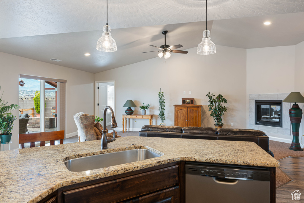 Kitchen featuring decorative light fixtures, sink, stainless steel dishwasher, a tile fireplace, and ceiling fan