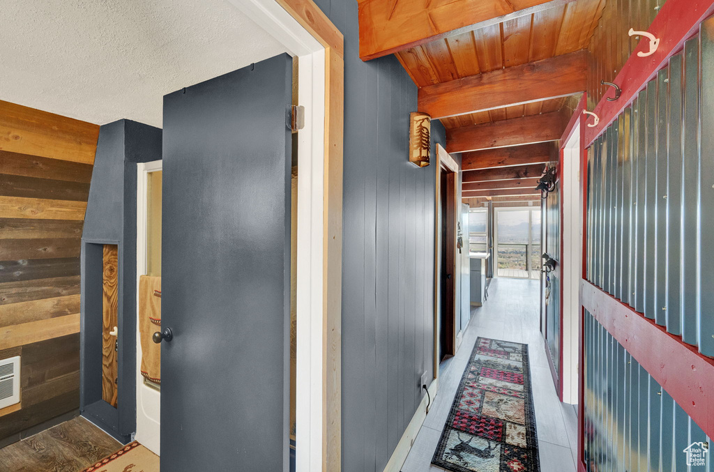 Hallway with wood-type flooring, wooden ceiling, beam ceiling, and a textured ceiling